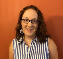 A person wearing glasses and a striped shirtDescription automatically generated